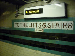 Old and new signage on the way to the lifts from the westbound platform